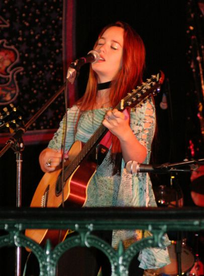 Fernanda playing a 12-string acoustic guitar